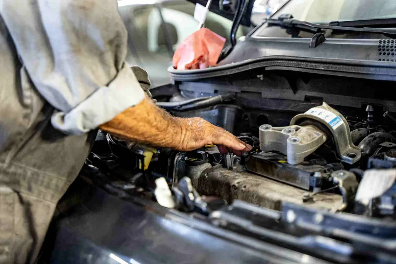 Mécanicien au travail sous le capot d’une voiture, dans l’atelier